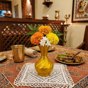 Kisméretű rézváza egy indiai étterem asztalán színes csokorral.