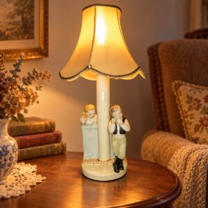 Figurákkal díszített porcelán asztali lámpa sárga textilernyővel, vintage szobában / Porcelain table lamp decorated with figurines and a yellow fabric shade in a vintage room