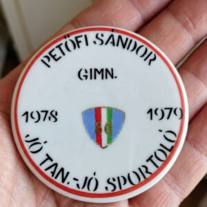 A round white vintage Hollóháza porcelain commemorative plaque in its original red silk-lined presentation box, featuring Hungarian text and a tricolor shield from 1978-1979. The back shows the green Hollóháza maker's mark.