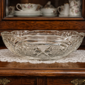 Interior lifestyle shot of the Bohemia bowl on a dark wooden sideboard with a lace doily and porcelain dishes in the background.