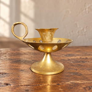 Réz sétáló gyertyatartó faasztalon, illusztratív élőkép / Brass chamberstick on a wooden table, illustrative lifestyle image