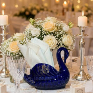 Kobaltkék hattyú szalvétatartó az esküvői asztalon.