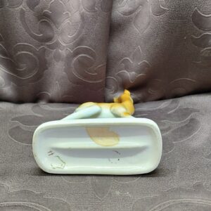 The underside of the figurine's base showing the factory markings and a small sticker residue.