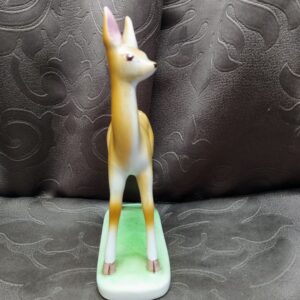 Frontal view of the porcelain fawn's face with its large, dark painted eyes.