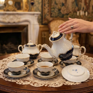 Complete 15-piece Zsolnay Pompadour II coffee set arranged on a wooden table with a lace tablecloth.
